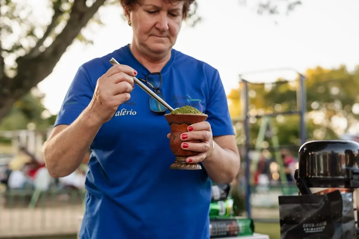 Mulher enchendo a cuia de chimarrão