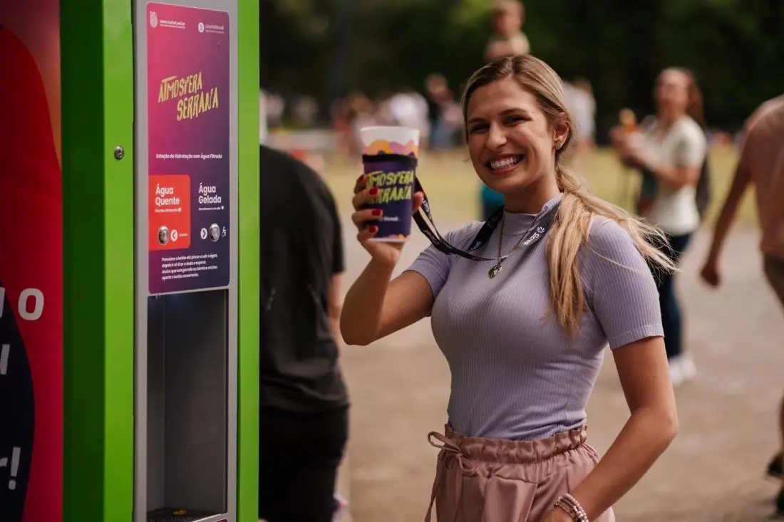 Mulher sorrindo com o copo cheio ao lado de uma estação Icehot